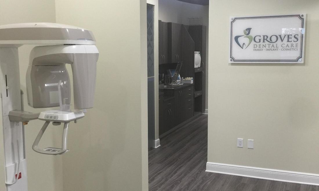 Modern dental office interior with wall-mounted equipment and Groves Dental Care signage visible.