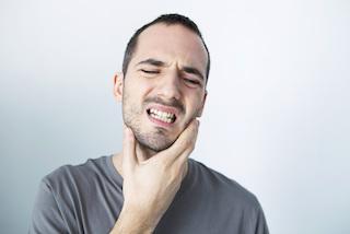 Man holding cheek in pain against white background, dental discomfort concept
