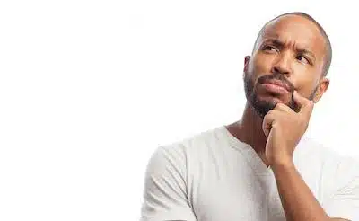 Man in casual shirt thinking thoughtfully with hand to chin against white background