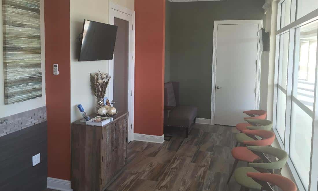 Modern dental office hallway with red walls, wooden flooring, and contemporary decor