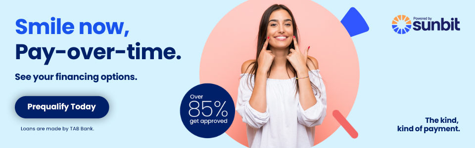 Woman smiling while holding piggy bank, promoting Sunbit dental payment plans.