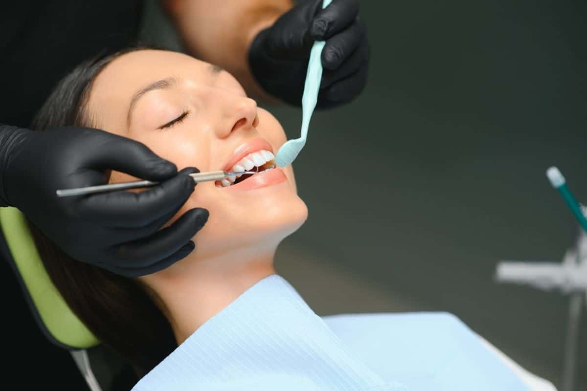 Dentist examining patient's teeth during dental procedure in clinical setting.