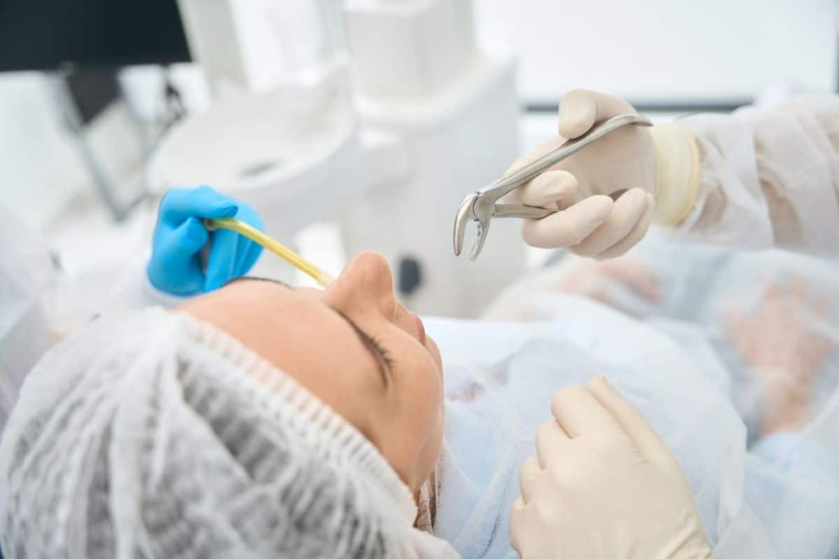 Dental professional in gloves examining patient's mouth with dental instruments in clinical setting.