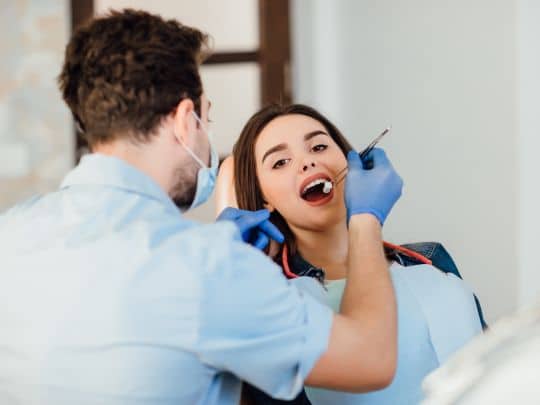 Dentist examining patient's teeth in dental office during checkup appointment