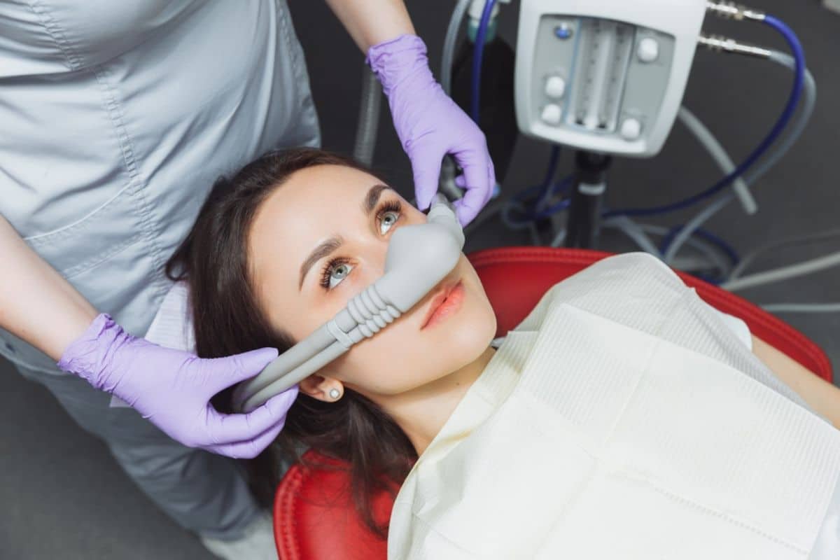 Dentist in purple gloves examining patient's teeth using intraoral scanner in dental office.